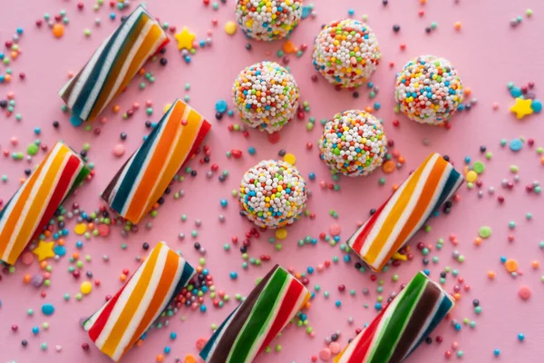 Flache lag mit verschiedenen bunten Süßigkeiten und Streusel auf rosa Hintergrund — Stockfoto