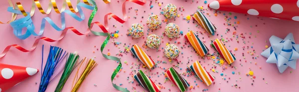 Top view of party caps near colorful sweets and serpentine on pink background, banner — Stock Photo