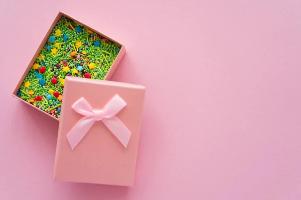 Vista superior de aspersiones en caja de regalo sobre fondo rosa - foto de stock
