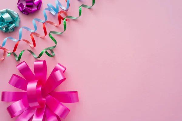 Vue du dessus des noeuds cadeaux et serpentine sur fond rose avec espace de copie — Photo de stock