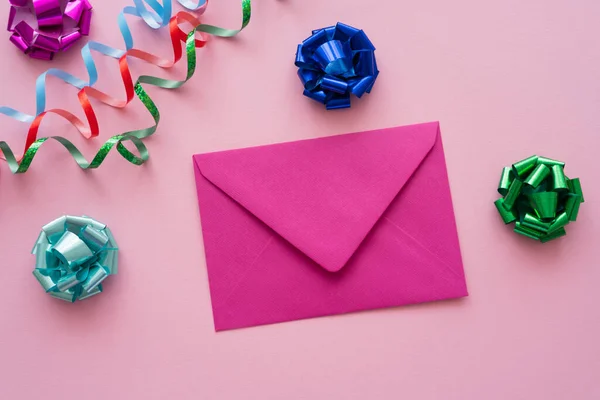 Вид зверху на конверт біля подарункових луків і змій на рожевому фоні — стокове фото
