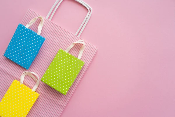 Vista superior de coloridas bolsas de compras con espacio de copia sobre fondo rosa - foto de stock