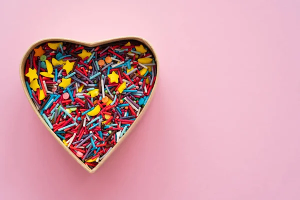 Vista superior de espolvoreos dulces en forma de corazón caja de regalo sobre fondo rosa - foto de stock