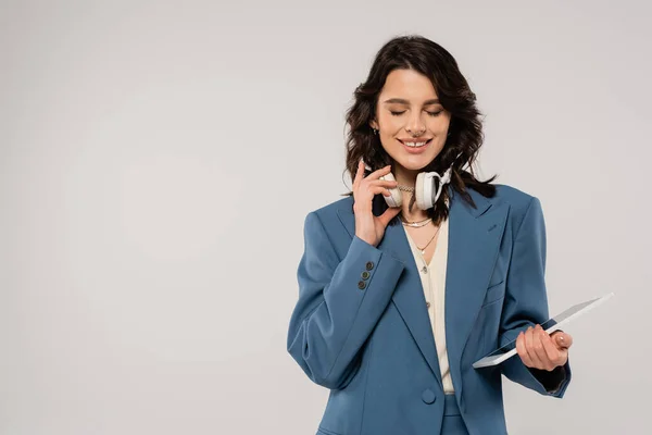 Happy brunette woman with wireless headphones and digital tablet isolated on grey — Stock Photo