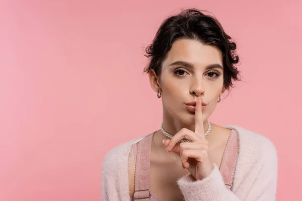 Giovane donna bruna mostrando il segno del silenzio e guardando la fotocamera isolata sul rosa — Foto stock