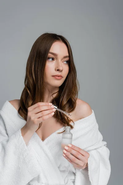 Young woman holding bottle and pipette with hair serum isolated on grey — Stock Photo