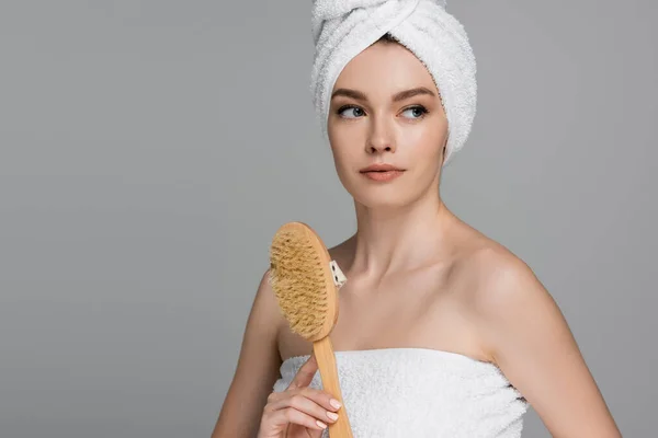 Young woman with towel on head holding wooden hair brush isolated on grey — Stock Photo