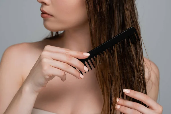 Vista cortada de mulher jovem com ombros nus pentear o cabelo molhado isolado no cinza — Fotografia de Stock
