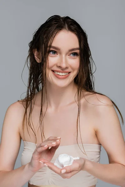 Junge und lächelnde Frau mit nassen Haaren, die Schaum in der Hand hält, isoliert auf grau — Stockfoto