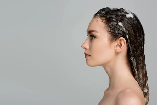 Side view of young woman with foamy and wet hair isolated on grey — Stock Photo