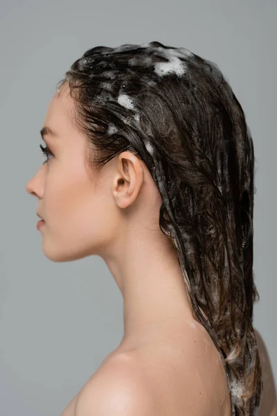 Profile of young woman with foamy and wet hair isolated on grey — Stock Photo