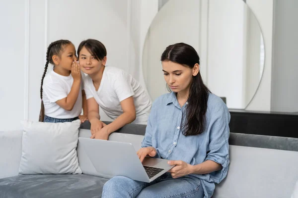 Mère à l'aide d'ordinateur portable près des enfants asiatiques parler à la maison — Photo de stock
