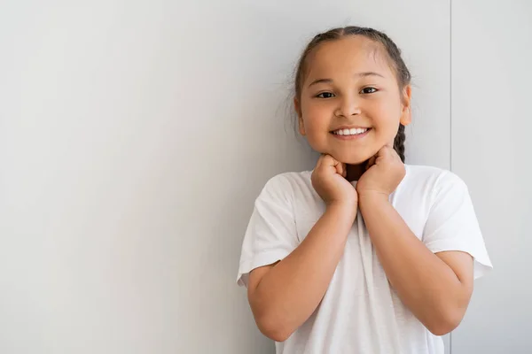 Positive asian girl looking at camera near wall at home — Stock Photo