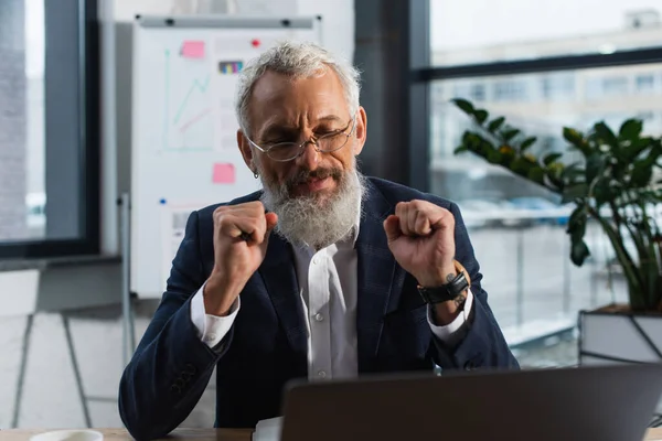 Smiling mature manger in suit using blurred laptop in office — Stock Photo