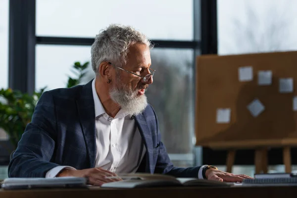 Mature businessman in suit working with papers in office in evening — Stock Photo