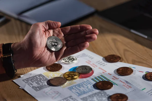KYIV, UCRAINA - 17 NOVEMBRE 2022: bitcoin d'argento in mano di uomo ritagliato vicino a carte con analisi di business — Foto stock