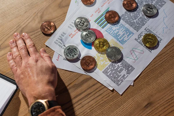 KYIV, UKRAINE - NOVEMBER 17, 2022: top view of silver and golden bitcoins on documents near hand of cropped businessman — Stock Photo