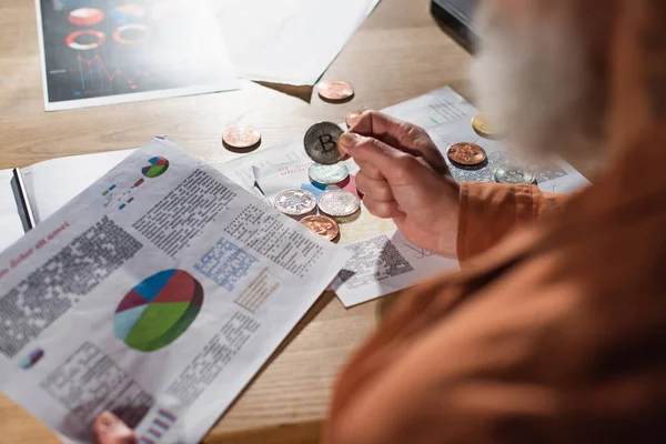 KYIV, UKRAINE - NOVEMBER 17, 2022: partial view of blurred man holding bitcoin and document with business analytics — Stock Photo