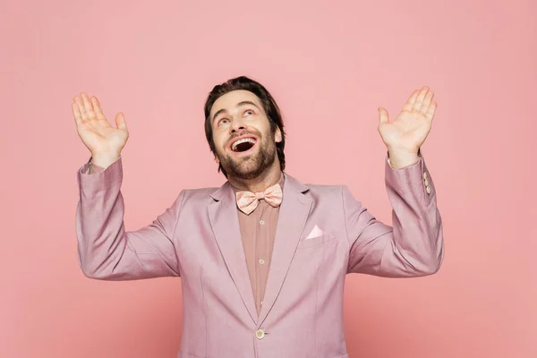 Fröhliche Moderatorin in Jacke und Anzug, die auf rosa Hintergrund aufblickt — Stockfoto