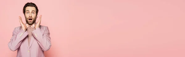 Geschockte Moderatorin in Sakko und Fliege blickt vereinzelt in die Kamera auf rosa Banner — Stockfoto
