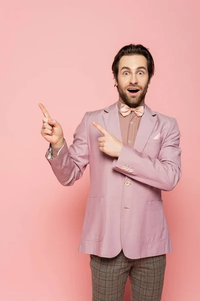 Amazed host of event pointing with fingers on pink background — Stock Photo