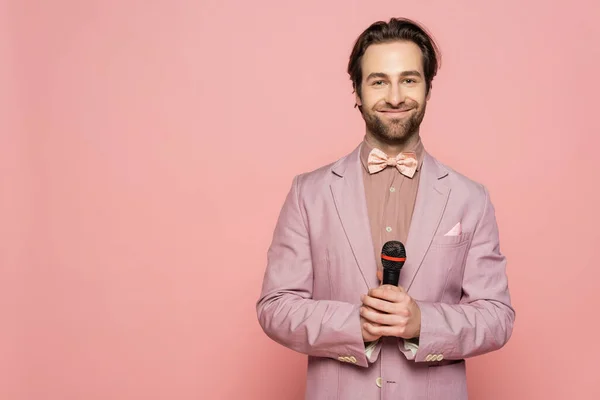 Young host of event holding microphone and looking at camera isolated on pink — Stock Photo