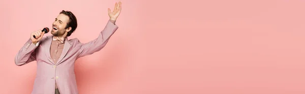 Elegante ospite di evento che canta al microfono su sfondo rosa, banner — Foto stock