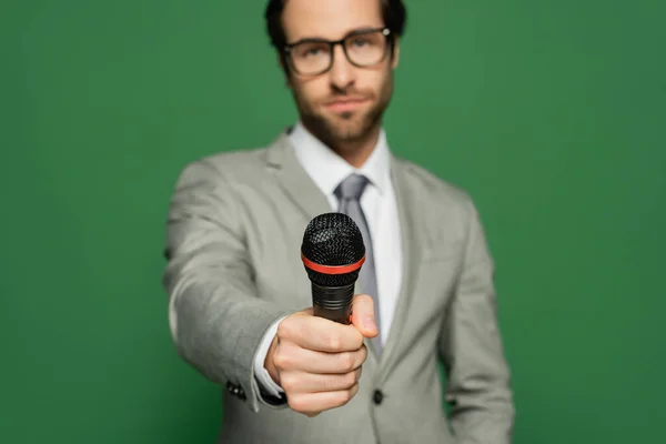 Periodista borroso en traje con micrófono aislado en verde - foto de stock