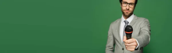 Newscaster desfocado em terno segurando microfone isolado no verde com espaço de cópia, banner — Fotografia de Stock