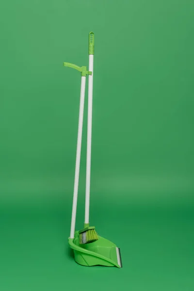 Balai et cuillère en plastique sur fond vert, concept de ménage — Photo de stock
