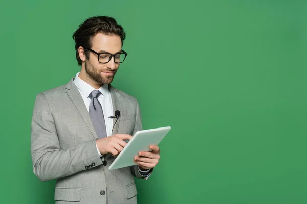 Periodista en gafas y traje usando tableta digital aislada en verde - foto de stock