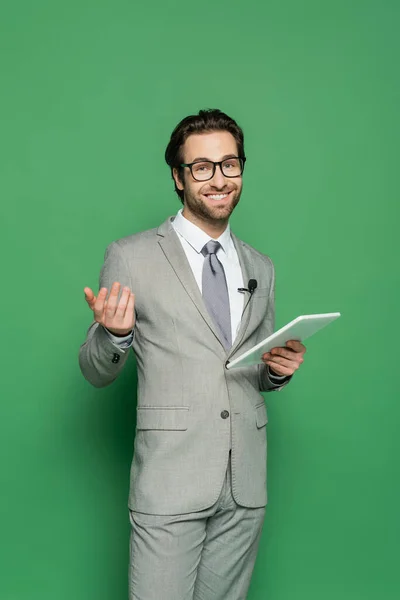 Fröhlicher Journalist in Brille und Anzug mit digitalem Tablet auf grünem Hintergrund — Stockfoto