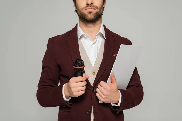 Cropped view of bearded host of event in formal wear holding microphone and clipboard isolated on grey — Stock Photo