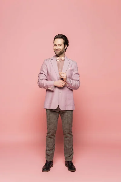 Полная длина веселый шоумен в костюме с бабочкой стоит на розовый галстук — стоковое фото