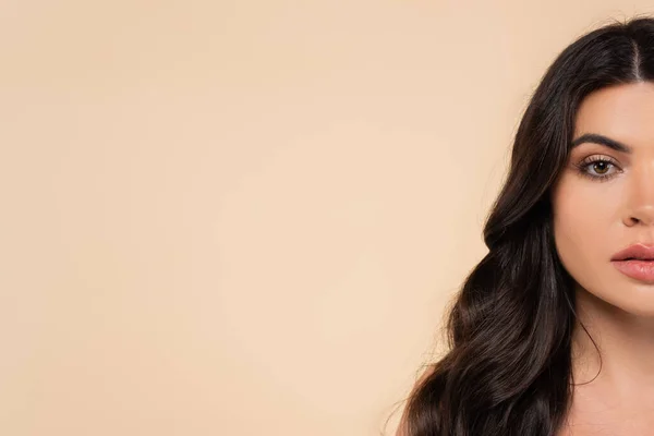 Cropped view of brunette woman with healthy hair looking at camera isolated on beige - foto de stock