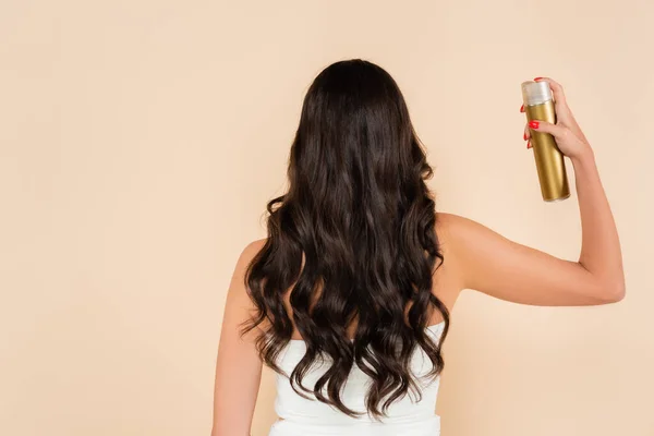 Back view of woman with wavy hairstyle using hairspray isolated on beige — Photo de stock