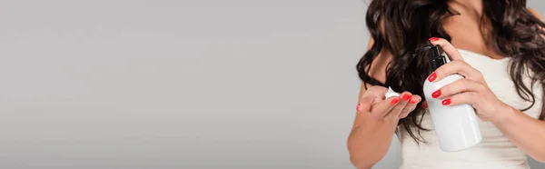 Vista parziale di donna bruna con capelli lunghi applicando schiuma styling a portata di mano isolata su grigio, banner — Foto stock