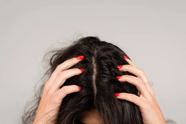 Vista ritagliata di donna bruna con manicure rossa che tocca la testa con capelli arruffati isolati su grigio — Foto stock