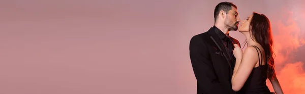 Sexy woman in black dress pulling tie while seducing man in formal wear on pink and grey, banner — Foto stock