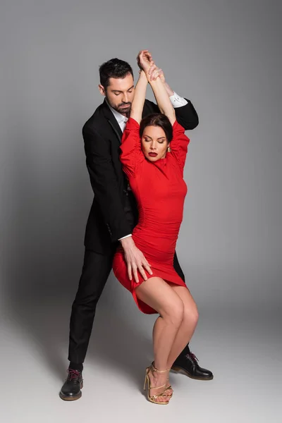 Full length of elegant man touching hip of sexy woman on grey background — Stock Photo