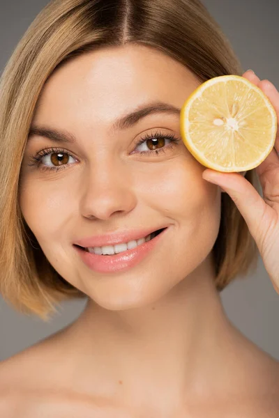 Portrait of happy young woman holding fresh lemon isolated on grey - foto de stock