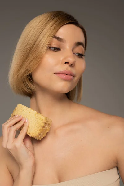 Young woman holding piece of organic honeycomb isolated on grey — Fotografia de Stock