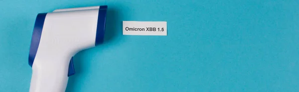 Top view of omicron xbb lettering near pyrometer on blue background, banner — Photo de stock