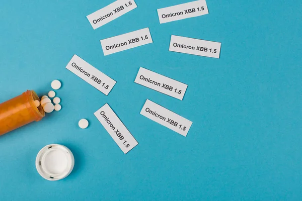 Top view of omicron xbb lettering near pills on blue background - foto de stock