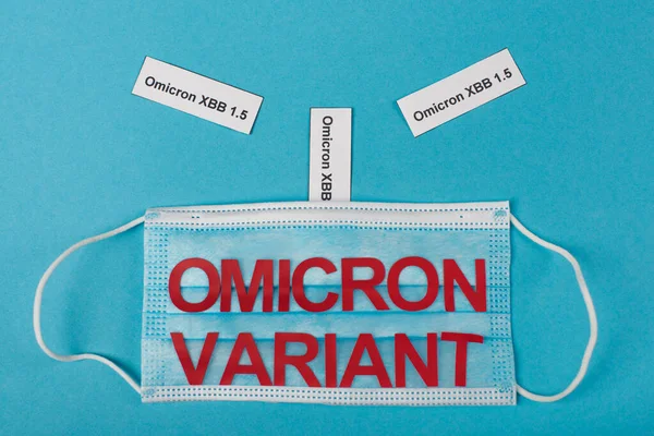 Top view of medical mask and omicron xbb lettering on blue background — Photo de stock