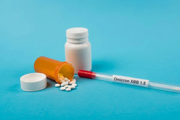 Throat swab with omicron xbb lettering near pills on blue background - foto de stock