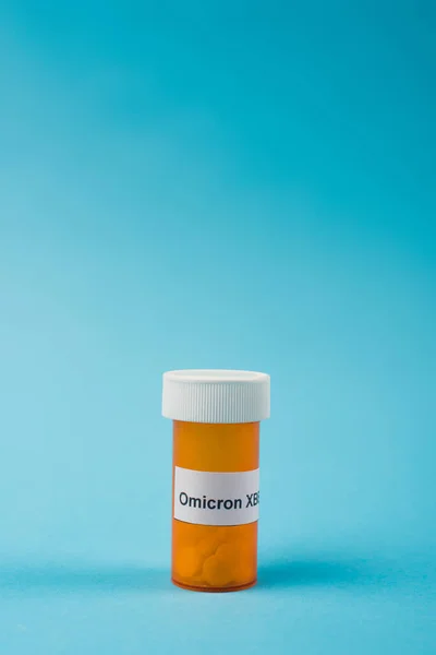Банка с таблетками и omicron xbb буквы на синем фоне — стоковое фото