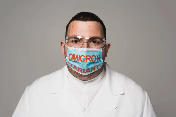 Scientist in goggles and medical mask with omicron variant lettering isolated on grey — Foto stock