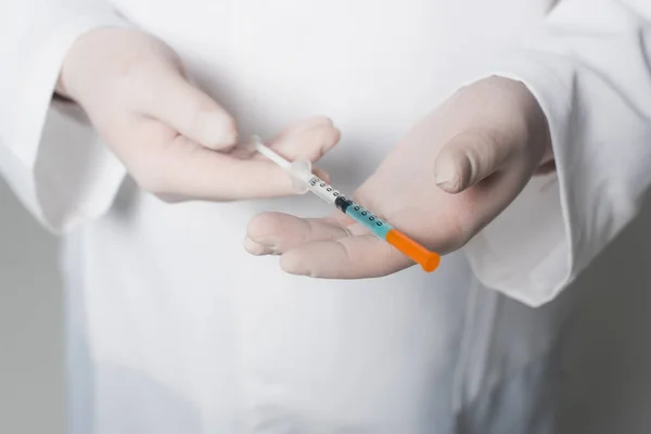 Cropped view of doctor in latex gloves holding syringe with vaccine on grey background - foto de stock