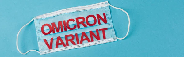 Top view of protective mask with omicron variant on blue background, banner - foto de stock
